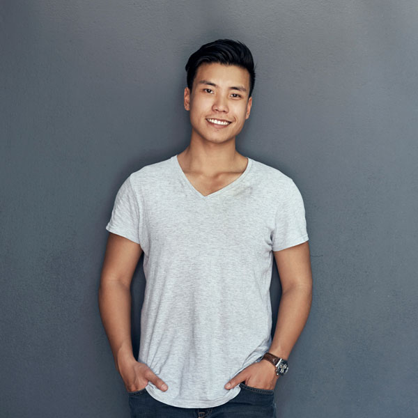 young man smiling with hands in pockets