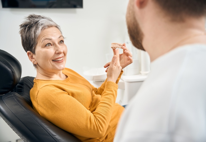 A smiling patient discussing dentures with a dentist in a dental clinic in Springboro, OH